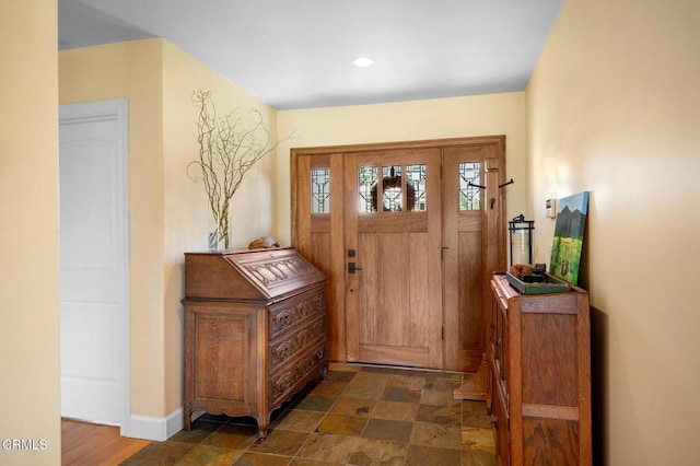 foyer with baseboards and stone finish floor