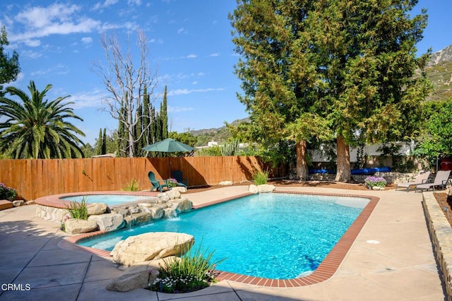 view of pool with a fenced in pool, a fenced backyard, a patio, and an in ground hot tub