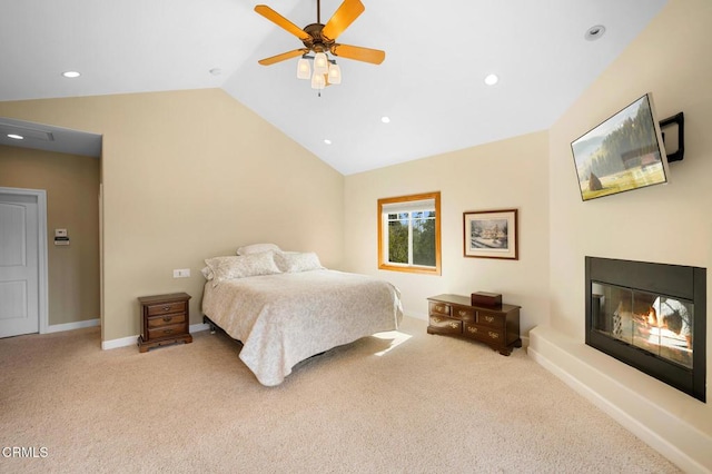 bedroom featuring lofted ceiling, baseboards, a glass covered fireplace, and carpet