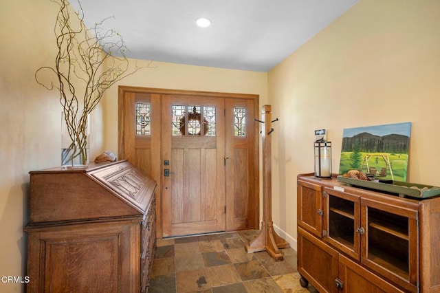 foyer with recessed lighting, stone finish floor, and baseboards