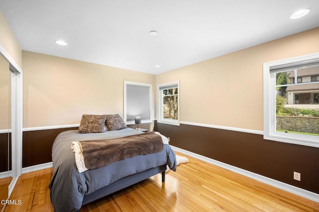 bedroom with a closet, recessed lighting, wood finished floors, and baseboards