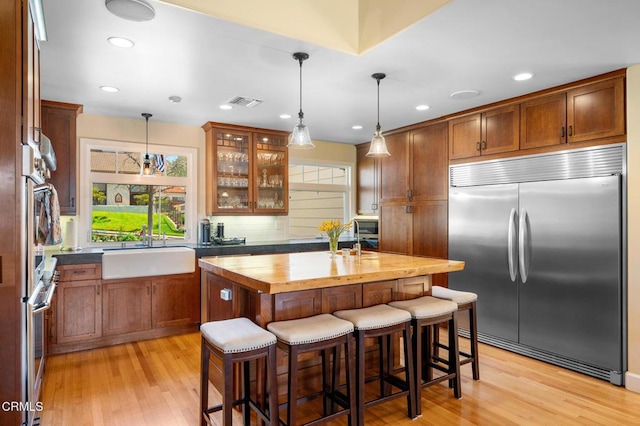 kitchen featuring a center island, a breakfast bar, light wood finished floors, appliances with stainless steel finishes, and a sink