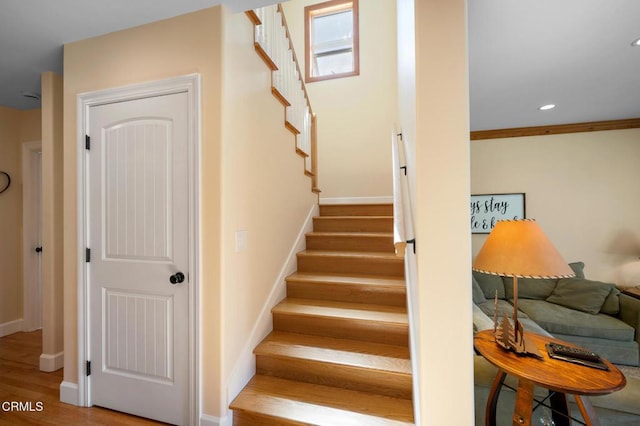 stairs with baseboards, wood finished floors, and recessed lighting