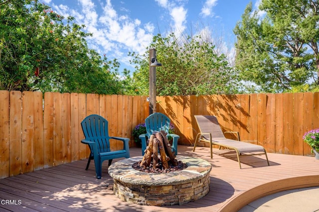 wooden terrace featuring fence and a fire pit