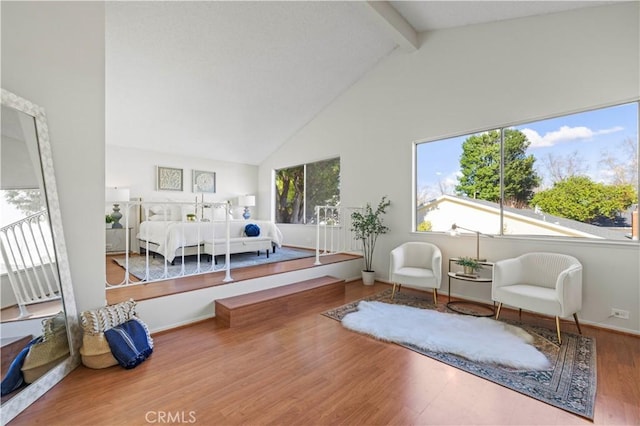 bedroom with beam ceiling, high vaulted ceiling, baseboards, and wood finished floors