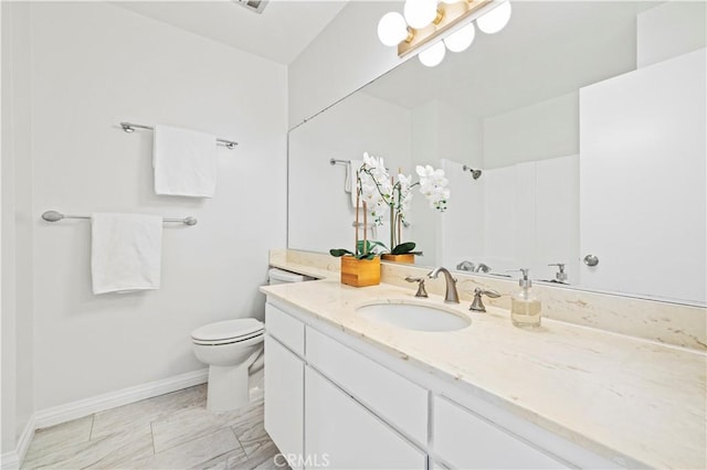 bathroom featuring vanity, toilet, a shower, and baseboards