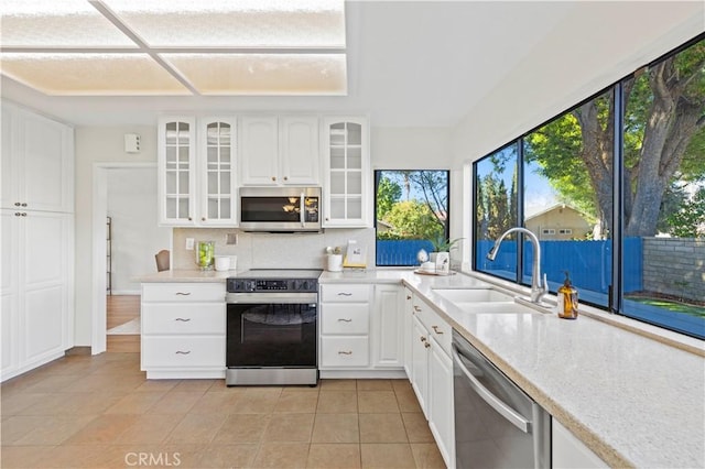 kitchen with tasteful backsplash, glass insert cabinets, appliances with stainless steel finishes, white cabinets, and a sink