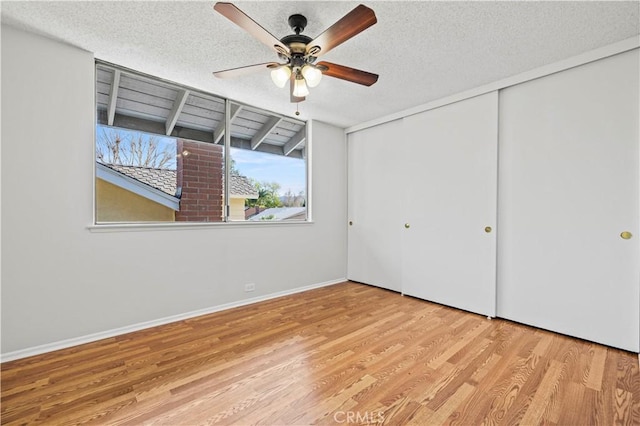 unfurnished bedroom with a ceiling fan, baseboards, wood finished floors, a closet, and a textured ceiling