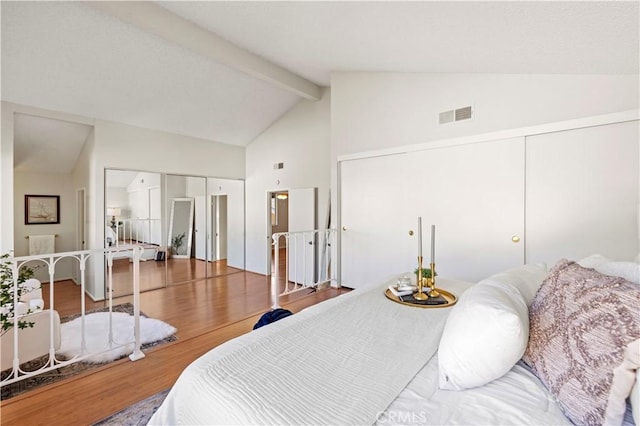 bedroom with beamed ceiling, high vaulted ceiling, visible vents, and wood finished floors