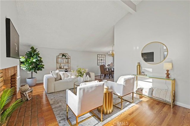 living area with baseboards, a notable chandelier, wood finished floors, and vaulted ceiling with beams