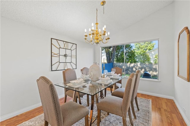 dining room featuring lofted ceiling, a textured ceiling, wood finished floors, baseboards, and a chandelier