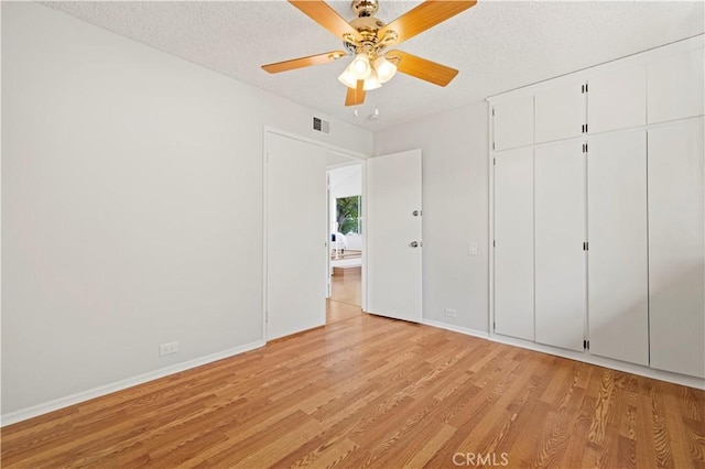 unfurnished bedroom featuring light wood finished floors, visible vents, baseboards, a closet, and a textured ceiling