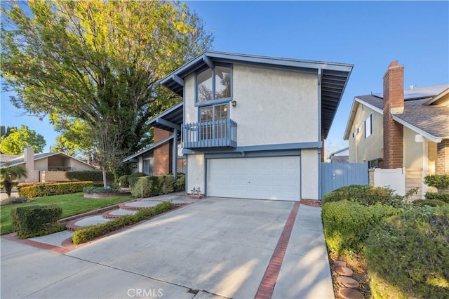 view of front of home with stucco siding, an attached garage, driveway, and fence