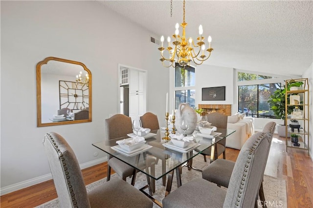 dining space featuring lofted ceiling, a notable chandelier, wood finished floors, and a textured ceiling