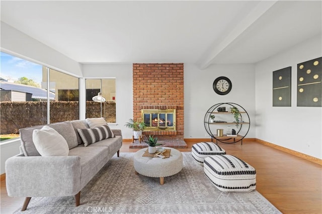 living room featuring a brick fireplace, baseboards, beam ceiling, and wood finished floors