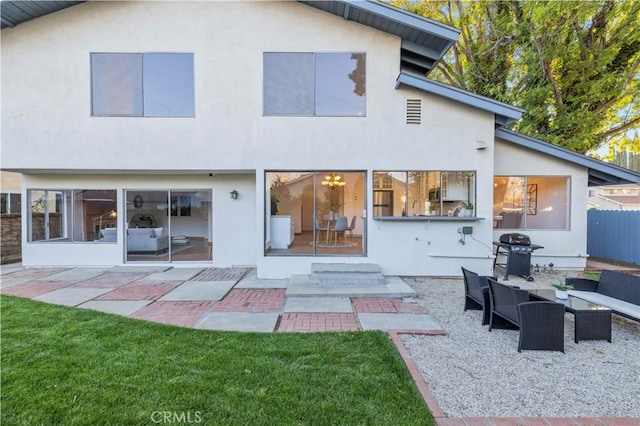 rear view of property featuring fence, stucco siding, an outdoor hangout area, a yard, and a patio area