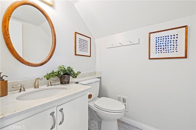 half bathroom with visible vents, toilet, baseboards, vanity, and vaulted ceiling