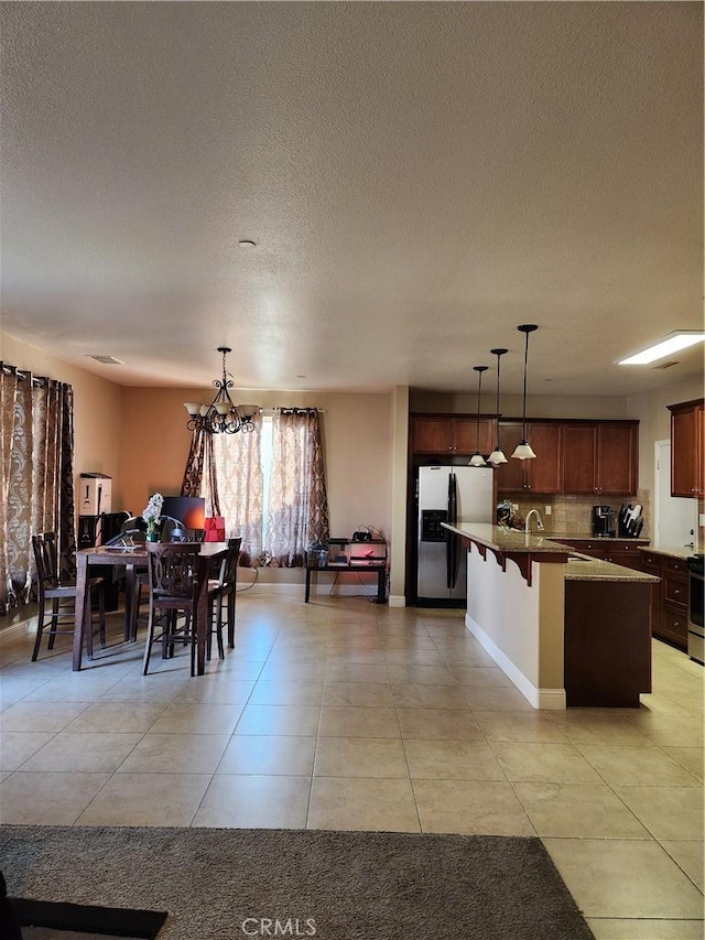 dining area with baseboards, a textured ceiling, and light tile patterned flooring