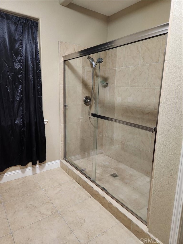 full bathroom with tile patterned flooring, a shower stall, and baseboards