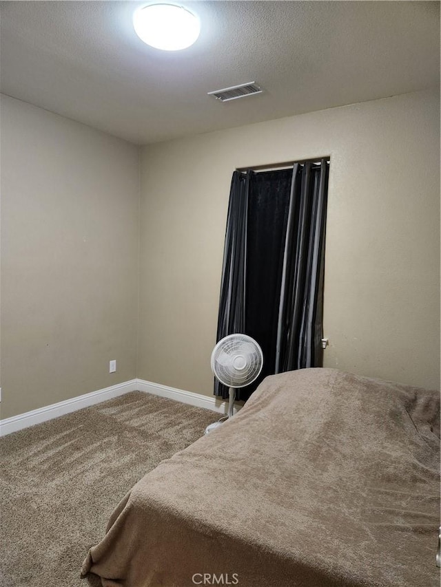 carpeted bedroom with a textured ceiling, visible vents, and baseboards