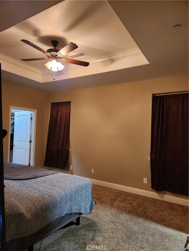 bedroom with carpet, a raised ceiling, visible vents, ornamental molding, and baseboards