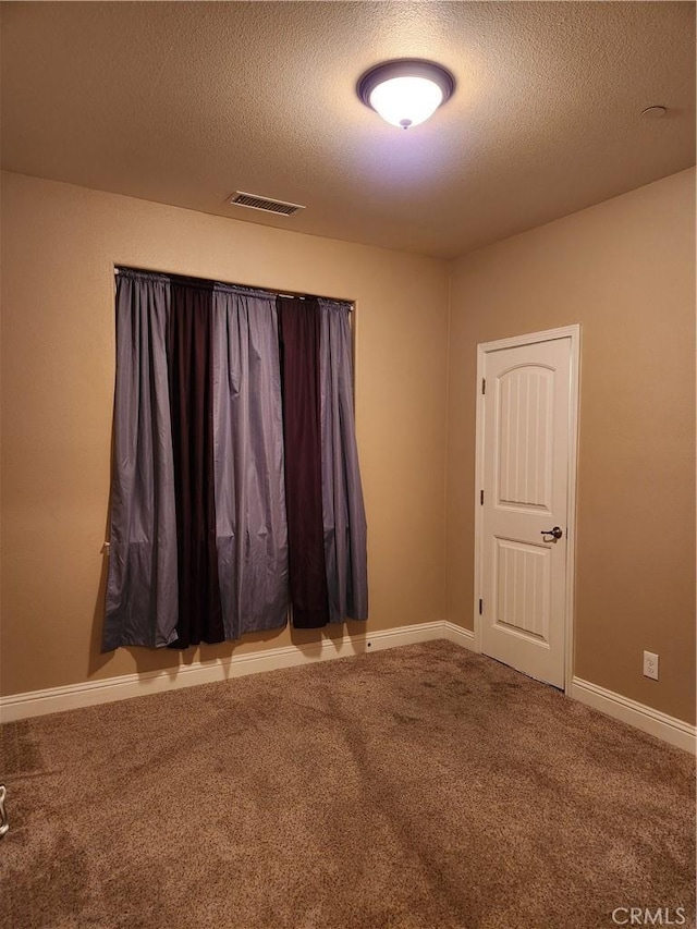 carpeted spare room with baseboards, visible vents, and a textured ceiling