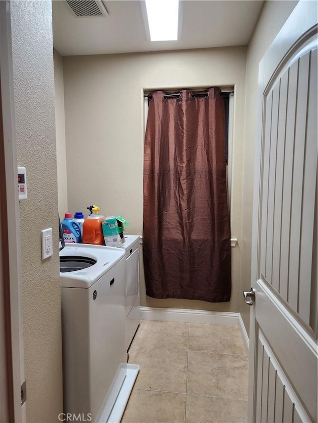 laundry area featuring washing machine and clothes dryer, visible vents, tile patterned flooring, laundry area, and baseboards