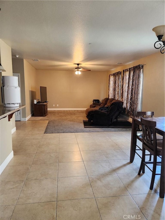 living room with light tile patterned floors, ceiling fan, baseboards, and a textured ceiling