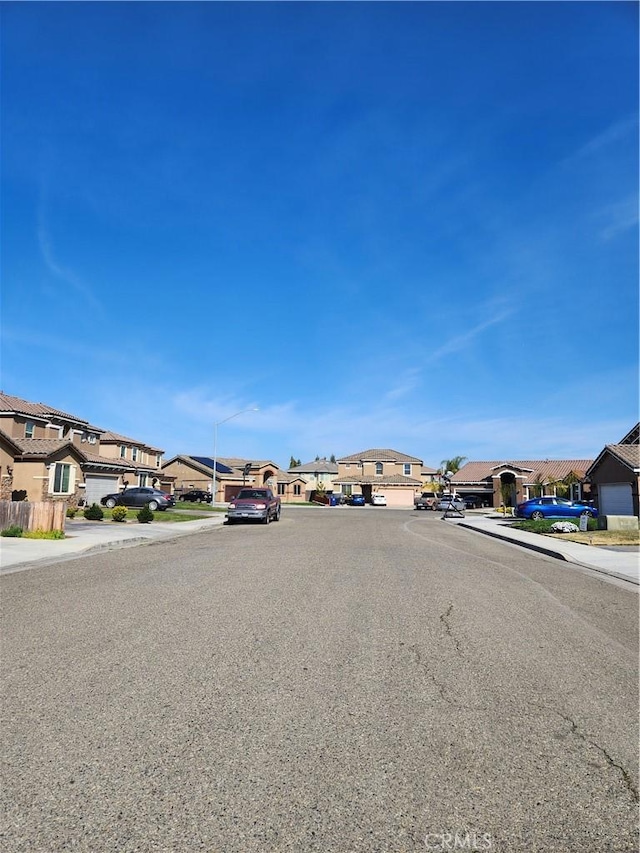 view of road with sidewalks, street lighting, a residential view, and curbs