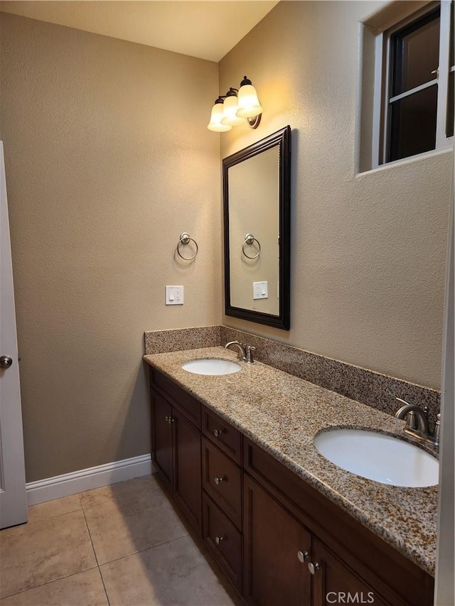 bathroom featuring double vanity, tile patterned flooring, baseboards, and a sink