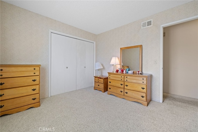 bedroom with carpet, a closet, visible vents, and wallpapered walls