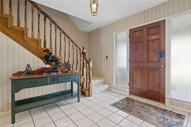 foyer featuring light tile patterned floors, stairs, and wallpapered walls