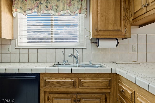 kitchen featuring tile counters, brown cabinetry, dishwasher, backsplash, and a sink