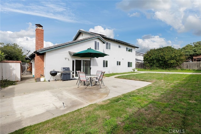 rear view of property featuring a patio area, a chimney, fence, and a lawn