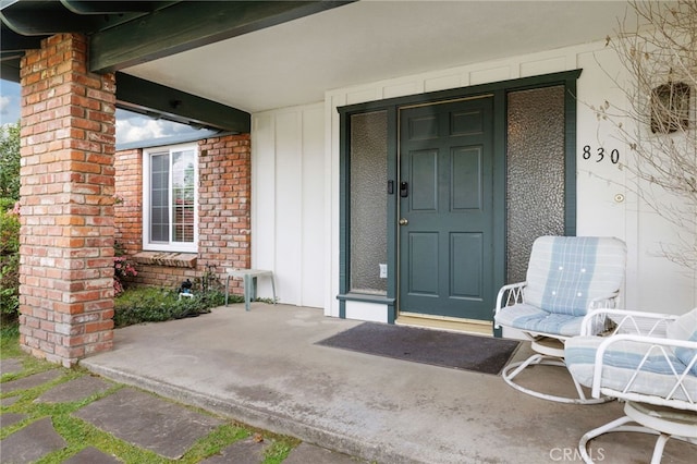 doorway to property with a porch and brick siding