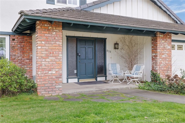 entrance to property featuring covered porch, brick siding, and board and batten siding