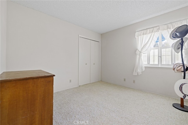 unfurnished bedroom featuring a closet, a textured ceiling, and carpet flooring