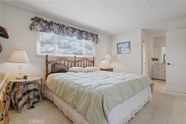 bedroom with connected bathroom, a textured ceiling, and light colored carpet