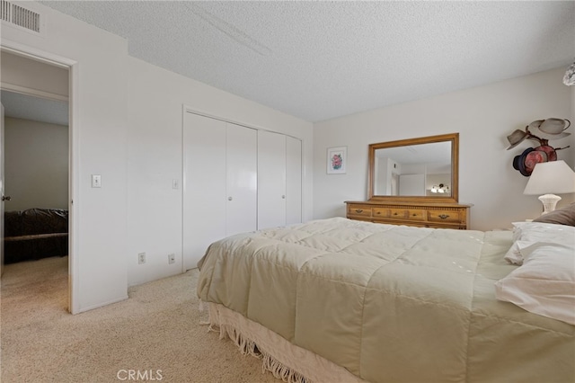 bedroom featuring carpet, a closet, visible vents, and a textured ceiling