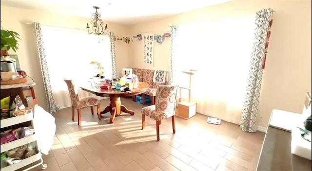 dining space with wood finished floors and an inviting chandelier