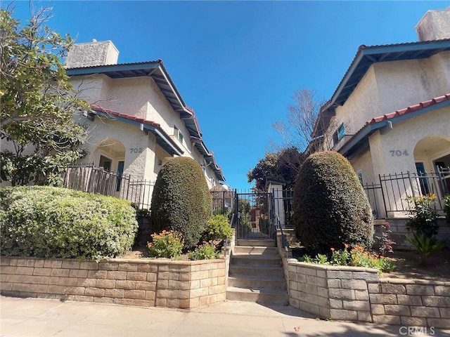 view of home's exterior with a tiled roof, a gate, a chimney, and stucco siding