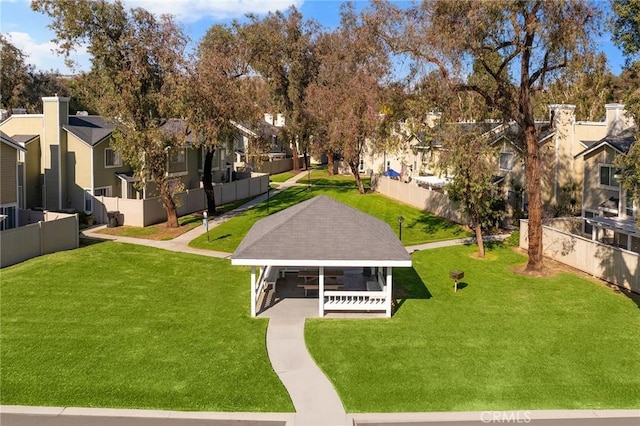 view of community with a residential view, fence, a gazebo, and a lawn