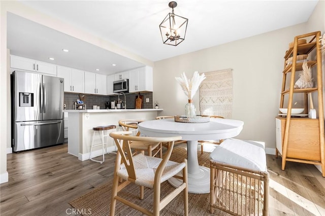 dining space with a notable chandelier, baseboards, wood finished floors, and recessed lighting