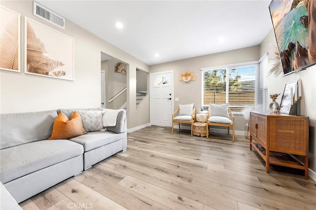 living room featuring baseboards, visible vents, stairs, light wood-type flooring, and recessed lighting