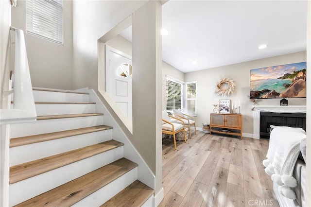 stairway featuring recessed lighting, a fireplace, baseboards, and wood finished floors