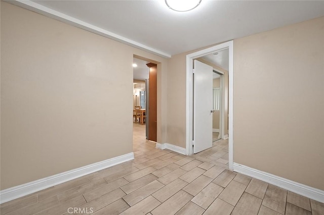 unfurnished room featuring wood tiled floor and baseboards