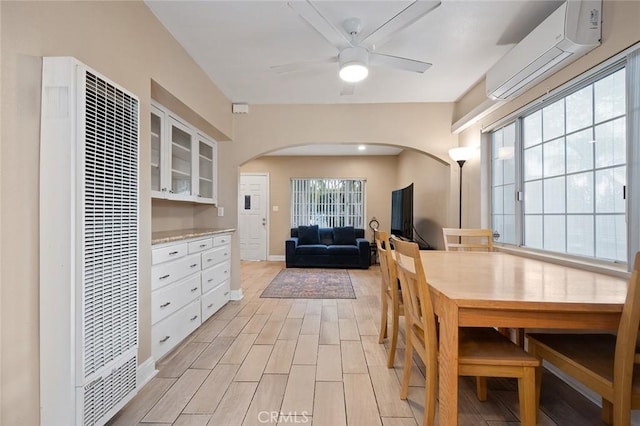 dining room with arched walkways, a ceiling fan, an AC wall unit, wood tiled floor, and a heating unit