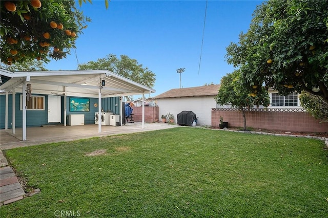 view of yard featuring washing machine and dryer, a patio area, and fence