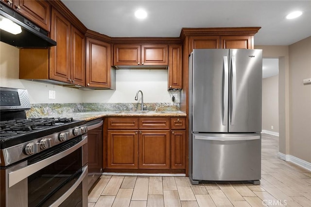 kitchen featuring recessed lighting, under cabinet range hood, stainless steel appliances, a sink, and brown cabinetry