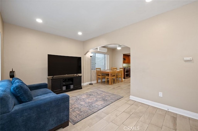 living area featuring arched walkways, wood finish floors, recessed lighting, and baseboards